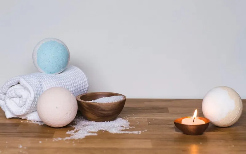 Toalla enrollada, sales y una vela encendida sobre una mesa de madera
