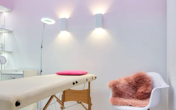 Sala de tratamiento luminosa con camilla, lámpara y silla