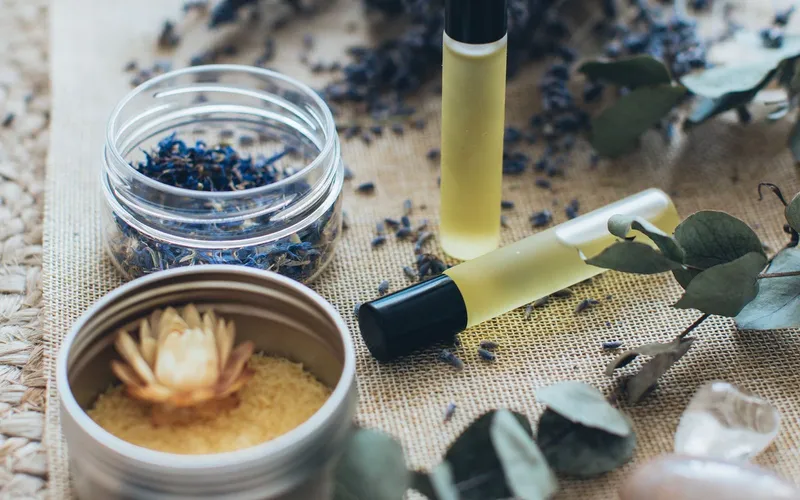 Aceites de masaje, lavanda seca y hojas de eucalipto sobre un mantel de yute