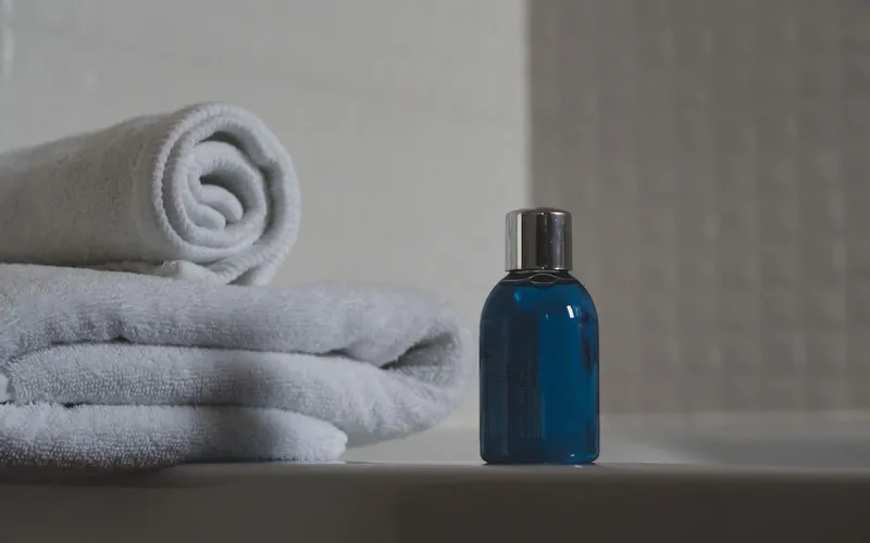 Toallas dobladas y un frasco azul sobre una repisa